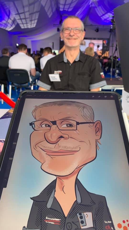 Erol zeichnet im Drogeriemarkt und ist von Kindern und Erwachsenen umringt, die für eine Karikatur Schlange stehen.