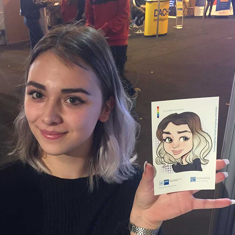 Ein junger Mann mit Lockenkopf sitzt beim CloudFest im Europa-Park Rust vor Erol, während seine fertige iPad-Karikatur auf dem Tisch sichtbar ist.