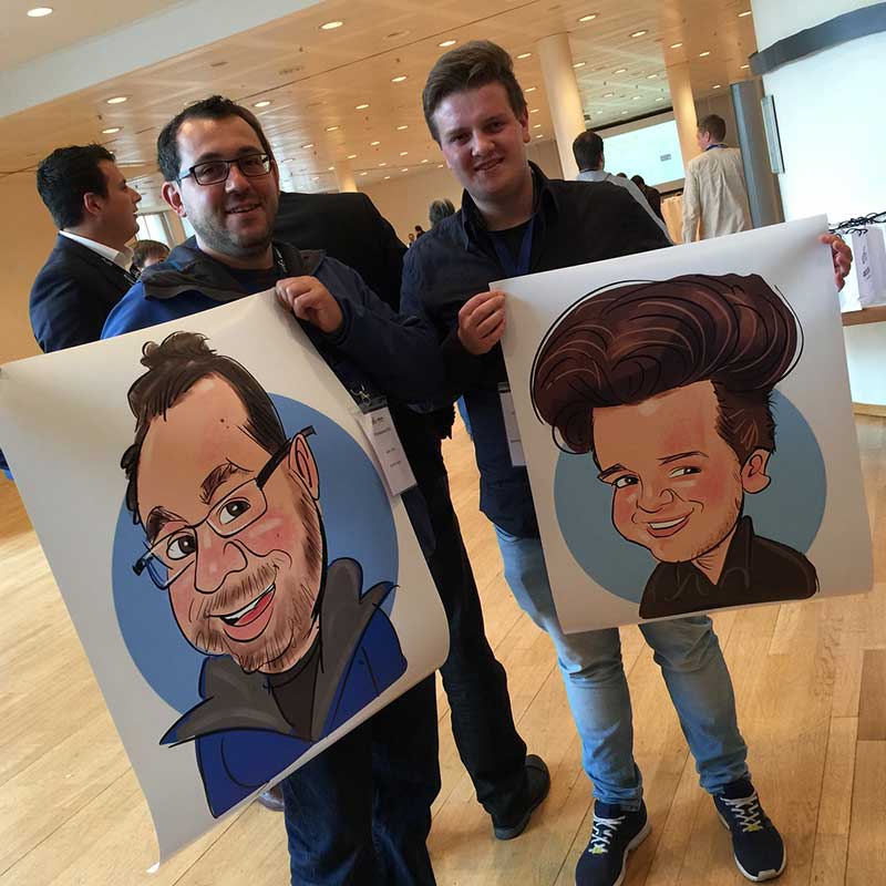 Erol steht zwischen zwei jungen Männern auf einer IT-Messe in Pforzheim; beide halten stolz XXL-Ausdrucke ihrer zuvor auf dem iPad gezeichneten Karikaturen, die im Rahmen einer Plotter-Vorführung erstellt wurden.