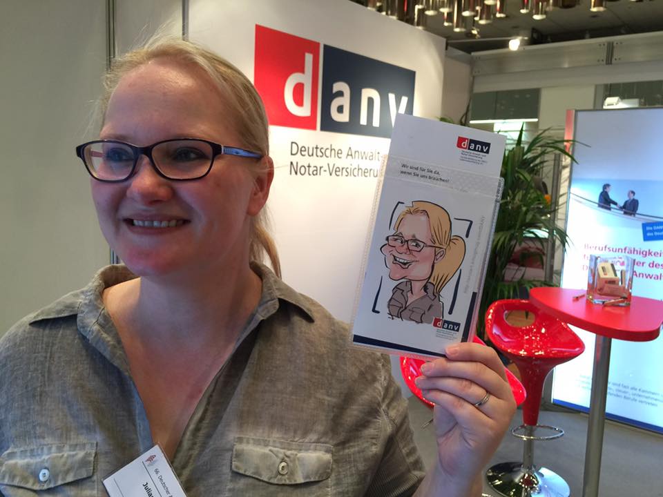 Eine Dame zeigt stolz ihre iPad karikatur gezeichnet von Erol am Messestand der danv
